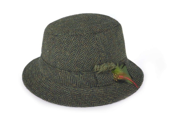 The Hanna Hats Walking Hat Tweed is a green and brown Irish tweed hat with a short brim, classic walking hat style, and a decorative feather in the hatband.